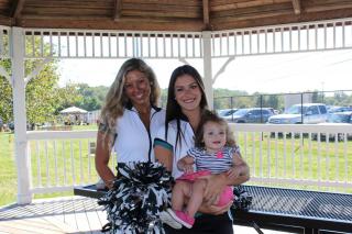 Two cheerleaders holding a baby